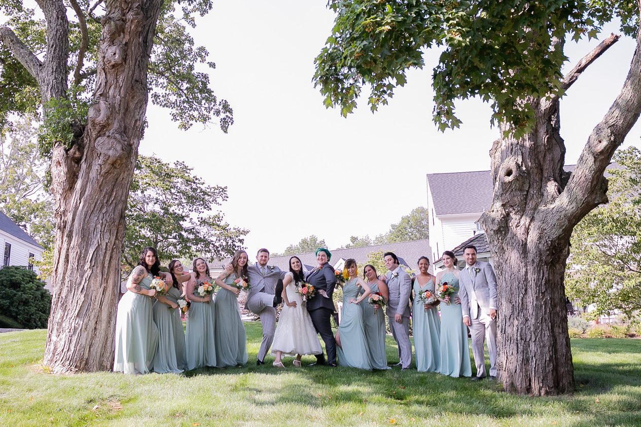 Wight Barn Sturbridge MA Queer Wedding - Wedding party in Grey Tuxes and Sage Dresses pose between two giant oak trees.